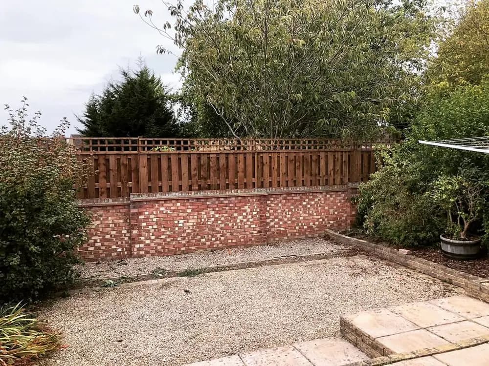 Hit and miss fencing with a trellis top, set on a low brick garden wall Hit and miss fencing with a trellis top, set on a low brick garden wall