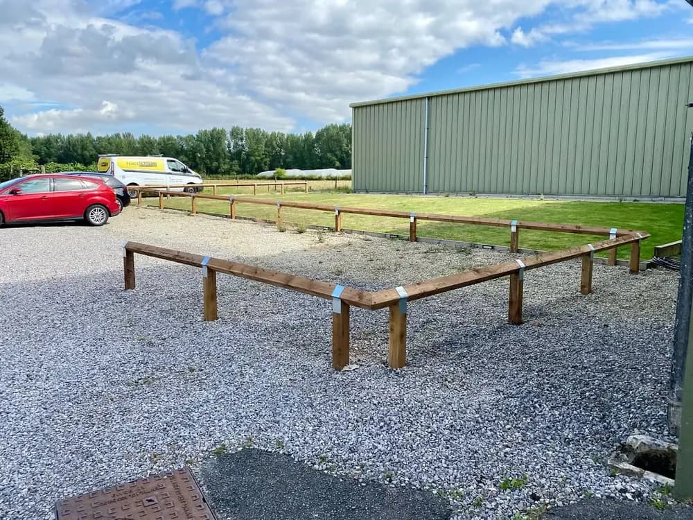 Knee-rail fencing edging a gravelled parking area beside an agricultural building Knee-rail fencing edging a gravelled parking area beside an agricultural building