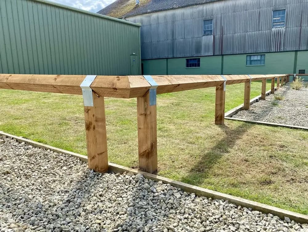 Close view of knee-rail fencing with galvanised straps at the post joints Close view of knee-rail fencing with galvanised straps at the post joints