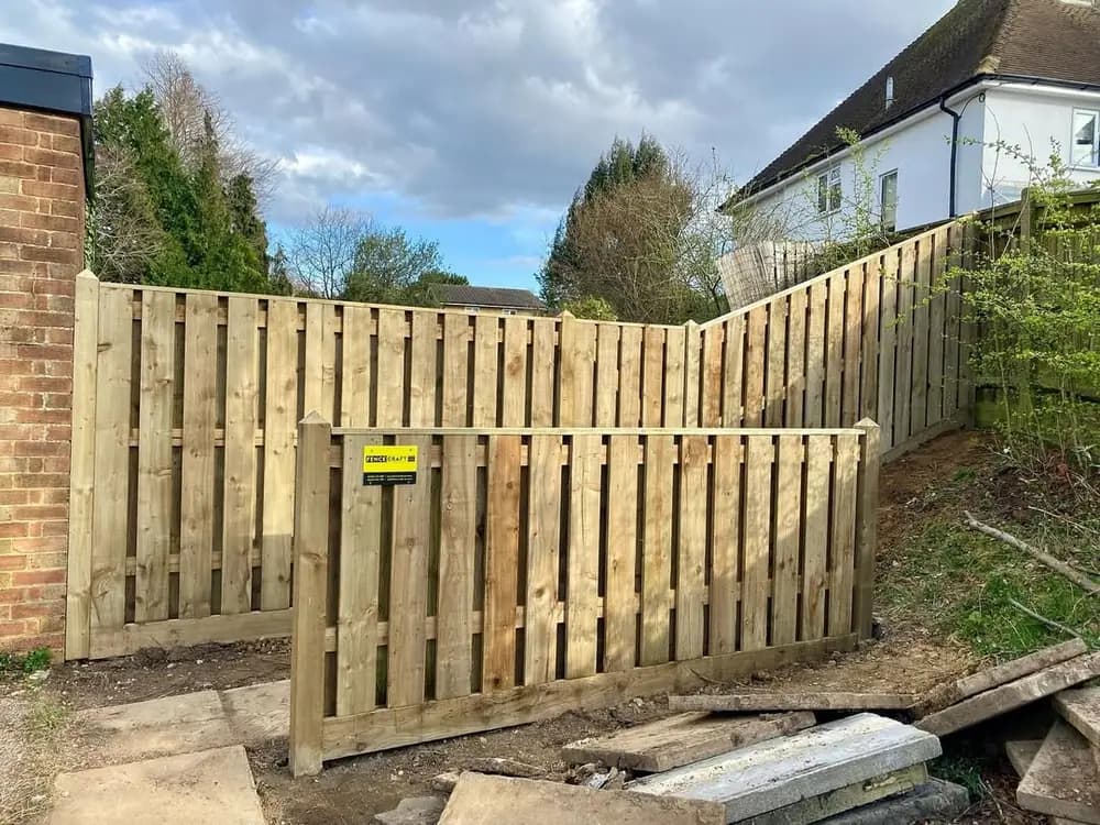 Vertical hit and miss fencing with a matching gate, part-built beside a house Vertical hit and miss fencing with a matching gate, part-built beside a house